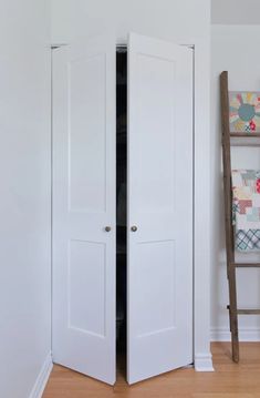 an open closet door in a white room with wood flooring and wall decorations on the walls