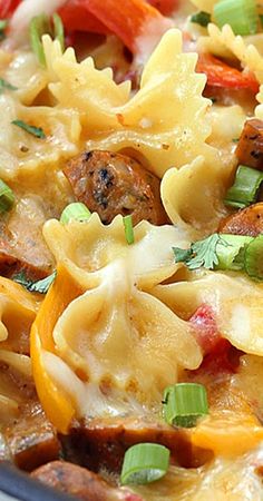 pasta with sausage, peppers and cheese in a pan