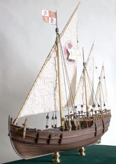 a wooden model ship with white sails