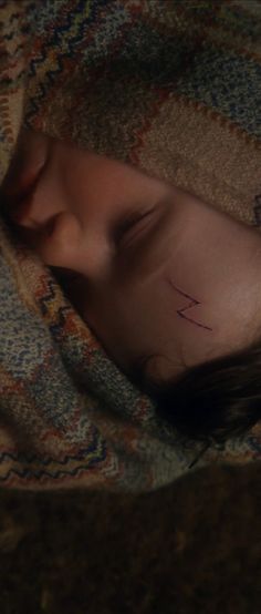 a young child laying on top of a bed under a blanket with the word love written on it