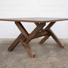 a wooden table sitting in front of a white garage door on concrete flooring next to a brick wall