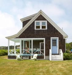 a small house with porches on the front and back sides, sitting in grass