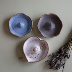 three ceramic bowls sitting on top of a table next to lavender flowers and a plant