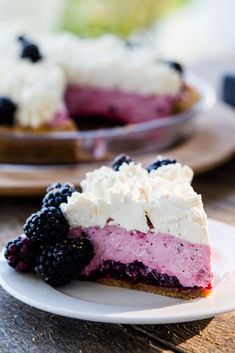 a slice of berry cheesecake with whipped cream and blackberries on a white plate