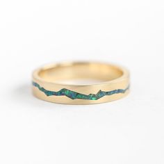 a gold ring with green and blue opal inlays on the inside of it