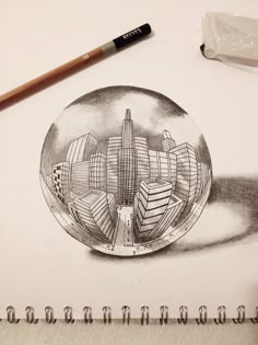 a drawing of a city in a glass ball with a pencil on the table next to it