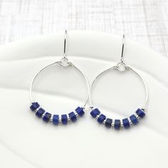 Add a touch of bohemian charm to your look with our Boho silver hoops featuring stunning lapis lazuli gemstones. Handcrafted with care, these sterling silver earrings are the perfect accessory for any free-spirited soul. Embrace your inner boho with these unique and stylish hoops! .925 Sterling Silver Measure approximately 1.125" in diameter Earrings Hang 1.75" from top of ear wire Lapis Lazui Gemstones Polished to a high shine Sent in a Gift Box with Polishing Cloth Handmade in Montana Bohemian Lapis Lazuli Earrings, Blue Sterling Silver Wire Wrapped Hoop Earrings, Blue Wire Wrapped Sterling Silver Hoop Earrings, Blue Bohemian Sterling Silver Hoop Earrings, Bohemian Blue Sterling Silver Hoop Earrings, Handmade Lapis Lazuli Jewelry For Everyday, Small Blue Sterling Silver Hoop Earrings, Sapphire Sterling Silver Hoop Earrings For Gift, Sapphire Sterling Silver Hoop Earrings As Gift