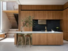 a kitchen with two stools next to a counter top and stairs in the background