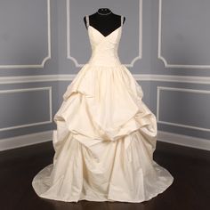 a wedding dress is displayed on a mannequin in front of a blue wall