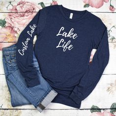 Perfect for a gift or for yourself to personalize by adding your favorite lake name to the sleeve.  Introducing our lightweight and stylish Lake Life Long Sleeve T-Shirt, crafted on the comfortable and premium Bella Canvas 3501 in the Heather Navy color. This is a unisex design so size down for a fitted look. Very soft and comfortable. Embrace the tranquil beauty of lake life with this soft and breathable long sleeve tee, perfect for those cool mornings and evenings by the water. Made from a blend of high-quality materials, this shirt offers the perfect balance of comfort and style, ensuring you stay cozy without feeling weighed down. Featuring a trendy lake-inspired design, whether you're lounging on the dock, enjoying a leisurely boat ride, or simply exploring the shoreline, this tee add Spring Long Sleeve Tops With Lettering, Long Sleeve T-shirt With Lettering, Casual Custom Text T-shirt For Fall, Fall Casual T-shirt With Custom Text, Casual Fall T-shirt With Custom Text, Custom Print Long Sleeve T-shirt For Spring, Long Sleeve T-shirt With Custom Print For Spring, Spring Long Sleeve T-shirt With Custom Print, Casual Long Sleeve Tops With Custom Text