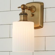 a bathroom light with a white glass shade on the wall next to a brick wall