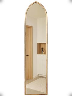 an arch shaped mirror in the middle of a room with white walls and beige carpet