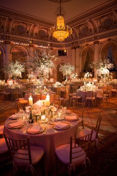 an elegant ballroom with chandeliers, tables and flowers on the centerpieces