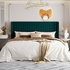 a bedroom with a green headboard and white sheets on the bed, along with decorative wall hangings