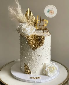 a white and gold birthday cake with flowers on top