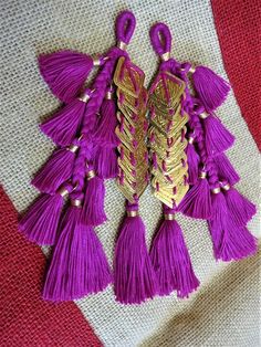 two purple tassels with gold accents on a red and white cloth fabric background