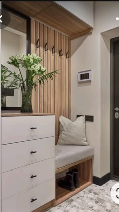 a room with a bench, mirror and flowers on the shelf next to the door