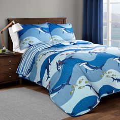 a bed with blue and white comforter in a bedroom next to a window overlooking the ocean