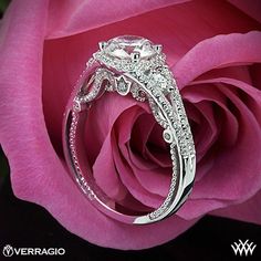 a close up of a pink rose with a diamond ring on it