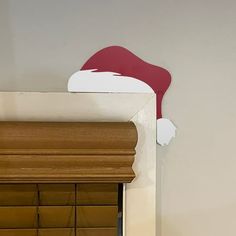 a cat sitting on top of a window sill next to a red and white santa hat