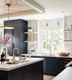 a kitchen with blue cabinets and white counter tops, gold faucets and brass accents