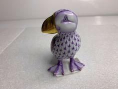 a purple and white bird figurine sitting on top of a counter next to a wall