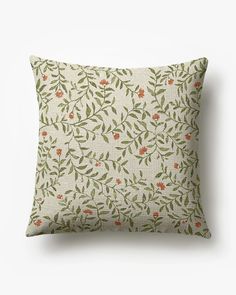 a pillow with an orange and green floral pattern on the front, sitting on a white surface