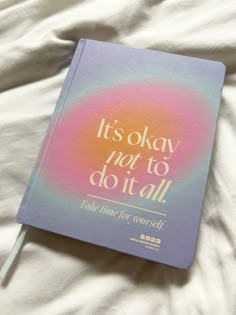 a book that is laying on top of a white sheet with the words it's okay not to do it all