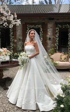 a woman in a wedding dress standing next to a table with flowers and cake on it