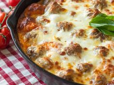 a casserole with meatballs and cheese in a pan on a checkered tablecloth