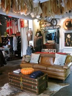 a living room filled with furniture and lots of hanging clothes on the wall above it