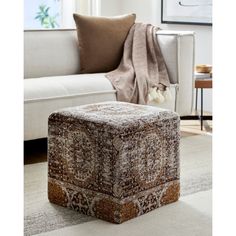 a living room with a white couch and a brown ottoman on the floor in front of a window