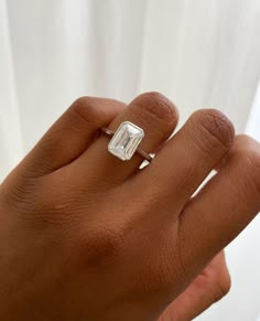 a woman's hand with a diamond ring on top of her left hand,