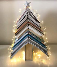 a christmas tree made out of books with lights around it and a star on top