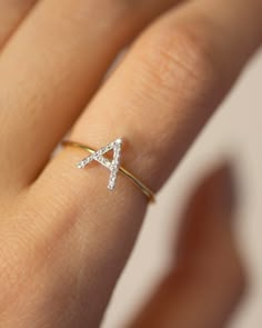 a woman's hand with a diamond ring on top of her finger and the letter a in the middle