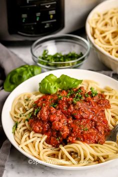 spaghetti with meat sauce in a white bowl next to an instant pressure cooker