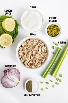 ingredients to make tuna salad laid out on a white surface with lemons, celery, onion, mayo, and seasoning