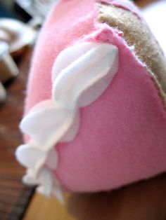 a pink and white stuffed animal sitting on top of a wooden table