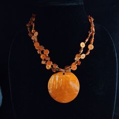 "Necklace featuring shell, plastic, ceramic and/or glass beads; beads from disassembling old pieces of jewelry Necklace length measures 18.5-22\"; glitter shell pendant measures 2.125\" in diameter Handmade. One of a kind"