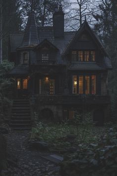 a house in the woods at night with lights on and stairs leading up to it