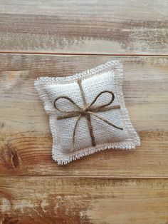 a white pillow with a brown bow tied to it on a wooden surface, sitting on top of a piece of wood