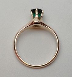 This is a 1940s-1950s classic! This is a six prong solitaire ring that has a 5.50 mm round synthetic (man made) green stone for the birth month of May. The stone has a fancy faceted top, similar to a rose cut on the top but with a pavilion like a modern cut round stone. There are some abrasions around the girdle, but the ring looks brand new other than that! The ring is stamped 10 kt and weighs 2.9 grams. Ring is sie 6.z Elegant Emerald Ring With Polished Round Band, Formal Solitaire Emerald Ring, Elegant Green Emerald Ring With Round Band, Timeless Green Round Band Jewelry, Classic Rings With Polished Finish For May Birthstone, Classic Emerald Ring With Tension Setting For Formal Events, Classic Polished Emerald Ring For Wedding, Classic Round Emerald Promise Ring, Modern Round Emerald Ring For Formal Occasions