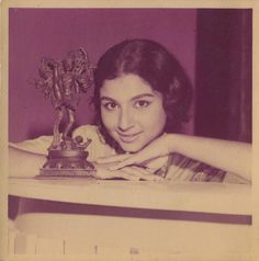 an old black and white photo of a woman with a statue in front of her