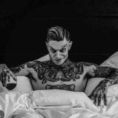 a man with tattoos on his chest laying in bed