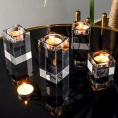 four clear candles sitting on top of a black table