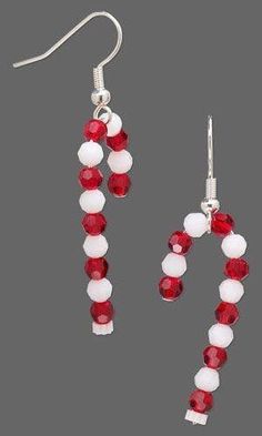 a pair of red and white beaded earrings with dangling earwires on a gray background