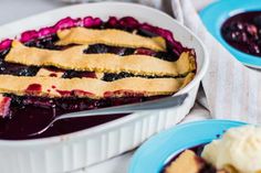 blueberry cobbler with ice cream and berries in the bowl next to another dish