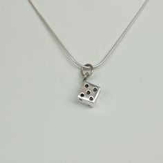 ▪︎ ONE sterling silver dice pendant/charm. ▪︎ This multipurpose piece can be used as a charm for neck chains, bracelet chains, hoops ,key chains etc ▪︎ Size: 8 x 12 mm Weight: 4.7 gm ▪︎ This pendant is handmade with hypoallergenic sterling silver. Most of my pieces are marked with a 925 silver stamp. ▪︎ Please note: This pendant comes WITHOUT the chain, however, you can add a snake chain in the required length while making your selection. You can also opt to choose other kinds of chains and brac Sterling Silver Box Chain Jewelry Gift, Silver Symbolic Square Pendant Jewelry, Symbolic Silver Square Pendant Jewelry, Silver Cube Jewelry For Gifts, Small Sterling Silver Jewelry With Charms, Sterling Silver Jewelry With Charms, White Gold Pendant Charms For Gift, White Gold Pendant Charms As Gift, Sterling Silver 925 Stamped Charms For Gifts