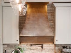 a kitchen with white cabinets and a copper range hood