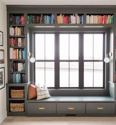 a window seat in front of a book shelf filled with books